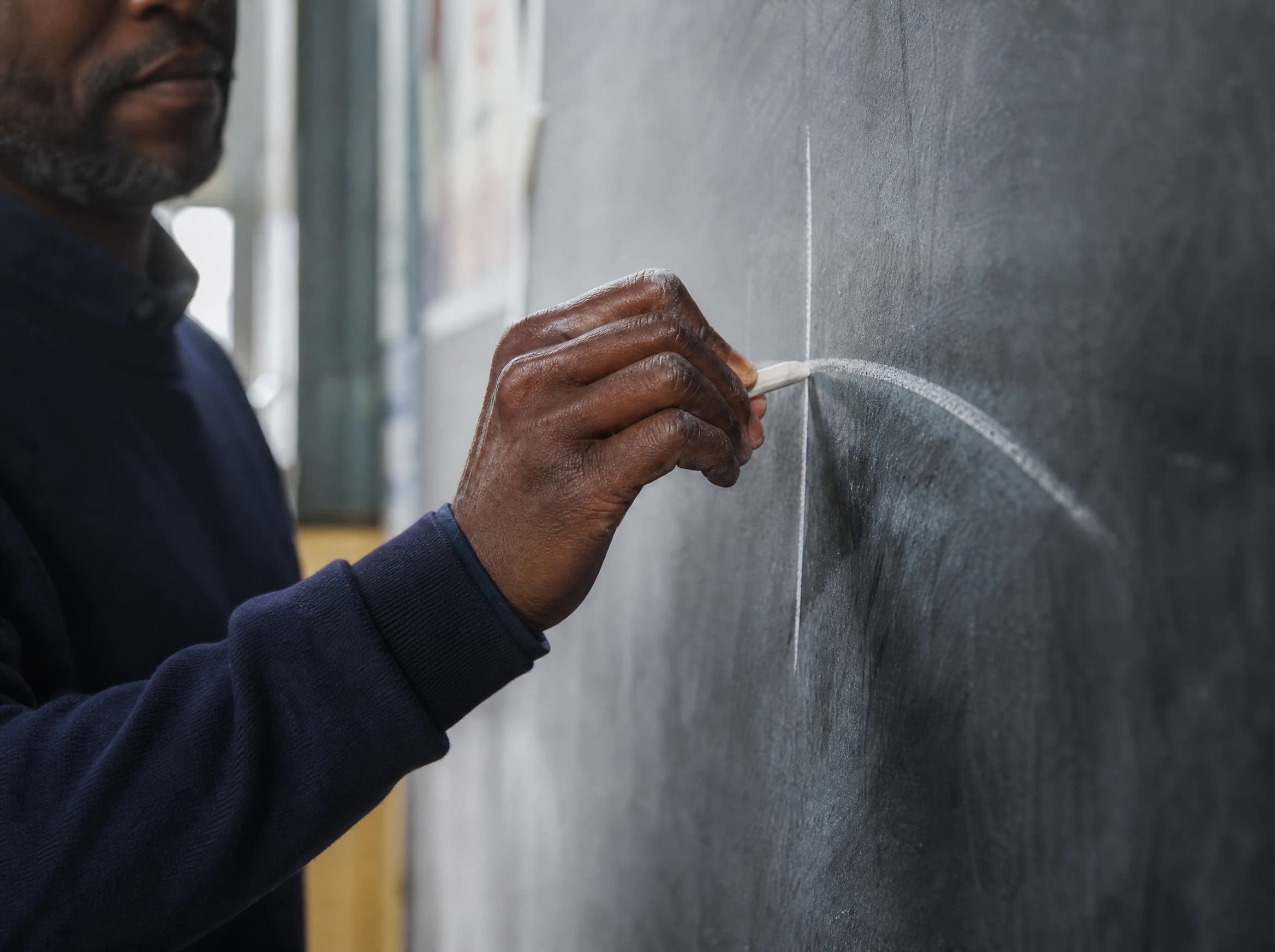 Teacher writing with chalk on a blackboard